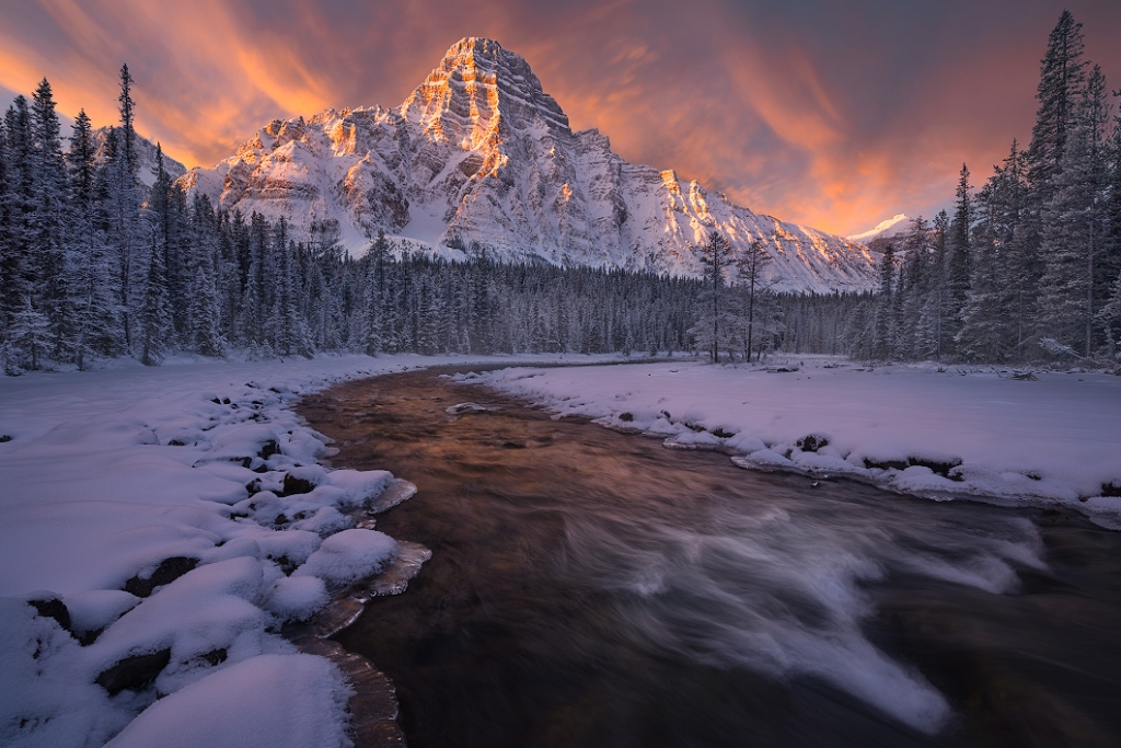 The sunrise at mount Chephren in winter. Taken beside a river that leads up to the peaks of the mountains. A nature photography print by Bryce Mironuck