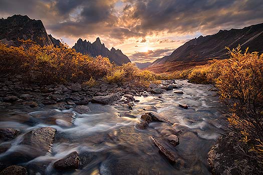A nature photography print taken at sunset in Tombstone Territorial Park in the Yukon. Pictured is a river leading to the mountains at Talus Lake. Nature photography print by Bryce Mironuck